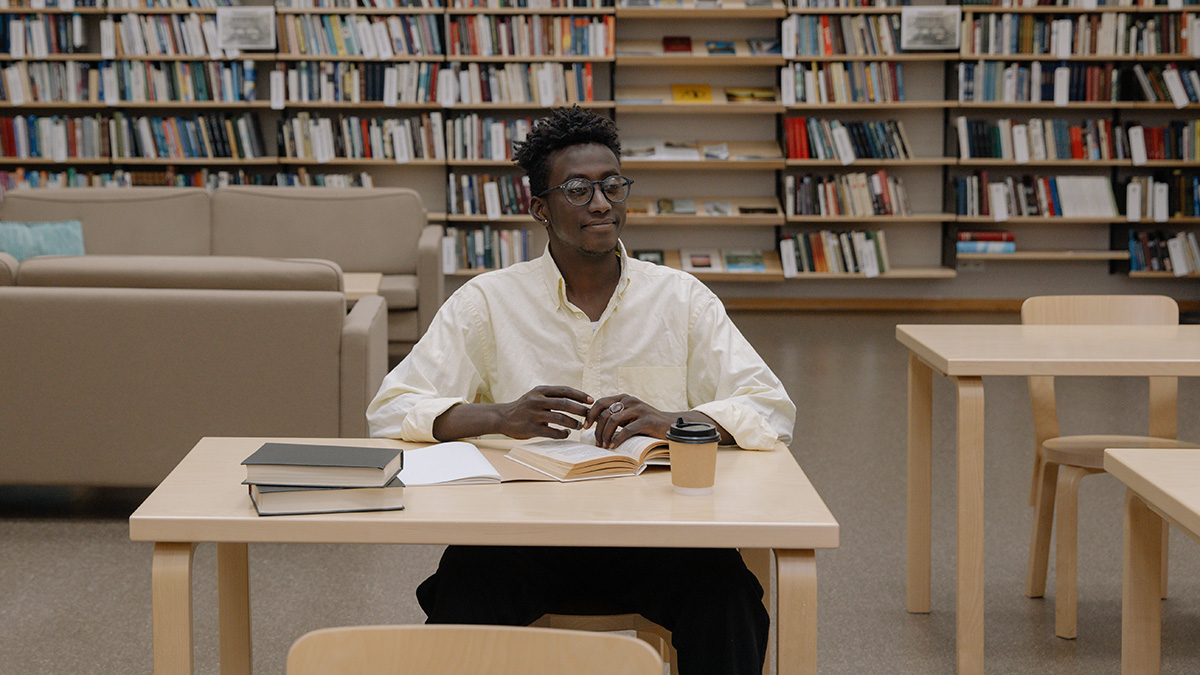 Junger Mann sitzt in der Bibliothek