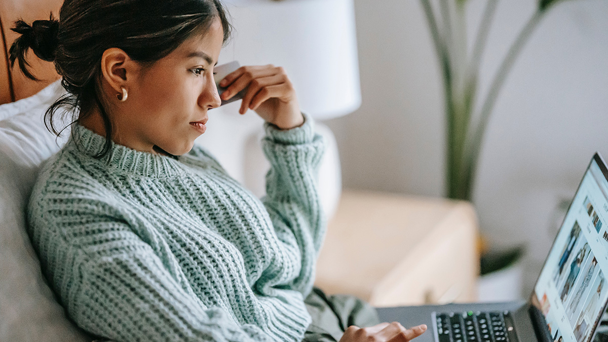 Frau am Laptop mit einer Karte in der Hand